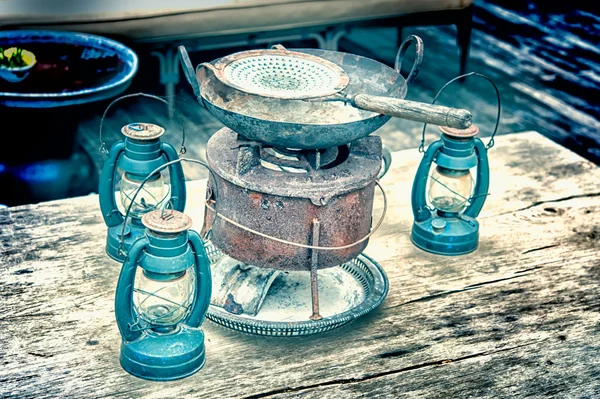 Керосиновая лампа и винтажная сковорода на деревянном столе — стоковое фото