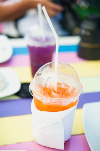 Стакан свежего апельсинового сока на разноцветном деревянном столе — стоковое фото