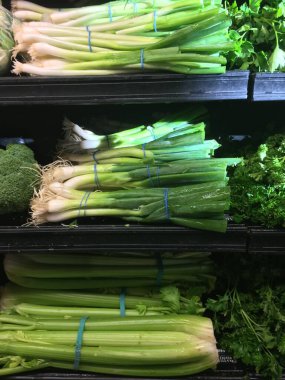 Marketteki raflarda yeşil soğan ve kereviz demetleri