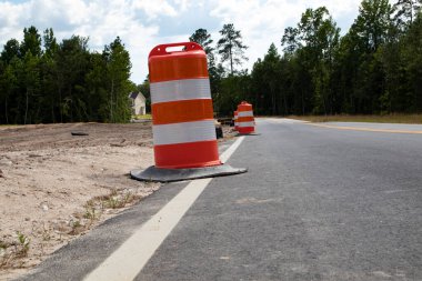 Yolun kenarında turuncu ve beyaz koniler var.