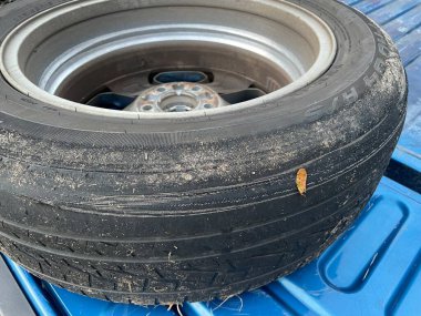 Mavi bir kamyonetin yatağında ters dönmüş kötü bir lastik.