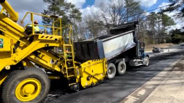 Augusta, Ga USA - 02: 16: 22: Yol döşeme ekibi bir Weiler asfalt besleyicisine tam dolu sıcak asfaltı boşaltıyor