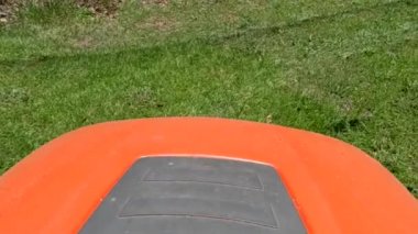 Çim biçme makinesi görüntüsü çimenleri yavaş çekimde ve böceklerle kesiyor.