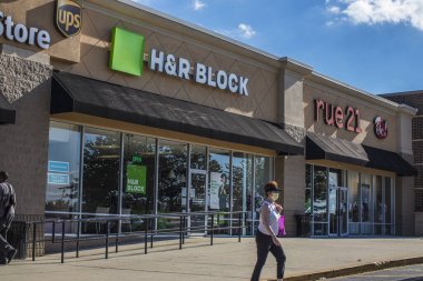 Dallas, Ga USA - 06 11 20: Woman wearing a face mask and HR block retail store strip mall Rue 21