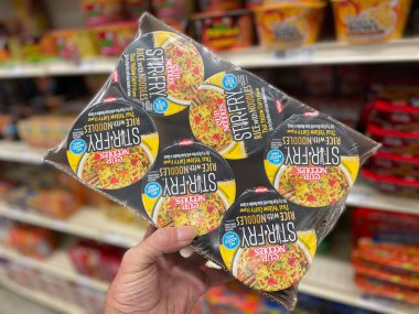 Grovetown, Ga USA - 07 24 22: Retail grocery store hand holding stir fry noodle cup full case