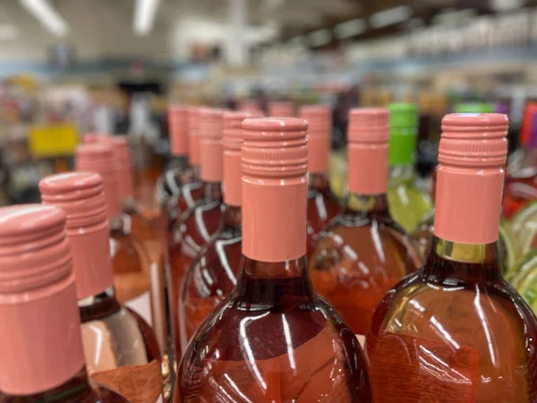 Rows of wine bottle tops pink wrapped tops on a retail shelf