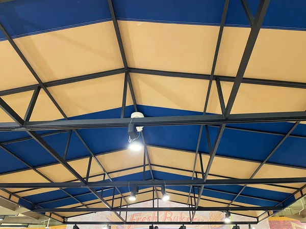 Looking up at a blue and beige soft roof top tent with bars and lighting