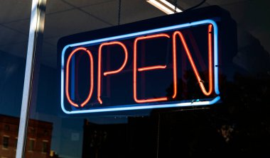 Neon OPEN sign hanging in a retail store window USA