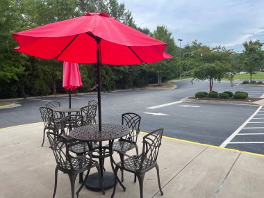 Dışarıda yemek masası ve şemsiye kaldırımdaki otoparka bakıyor.