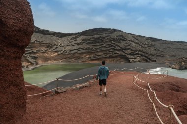 young man walks down the path towards the green puddle. The Gulf. Yaiza. Canary Islands