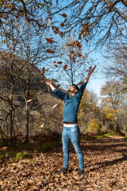 Kapat. Genç adam düşen sarı yapraklarla oynuyor. dikey bileşim