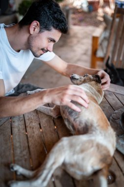 dikey kompozisyon. Genç adam bahçede bir köpekle etkileşime girer.