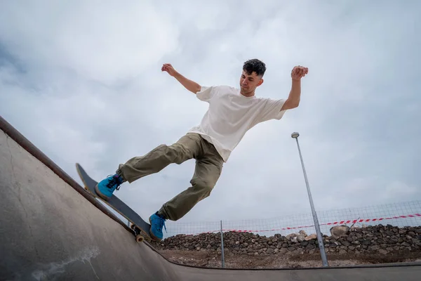 young male skater skates over the edge of a bowl at a skate park.