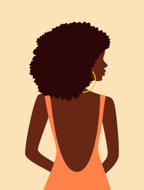 Beautiful african woman with curly hair in peach dress with open back looking over her shoulder