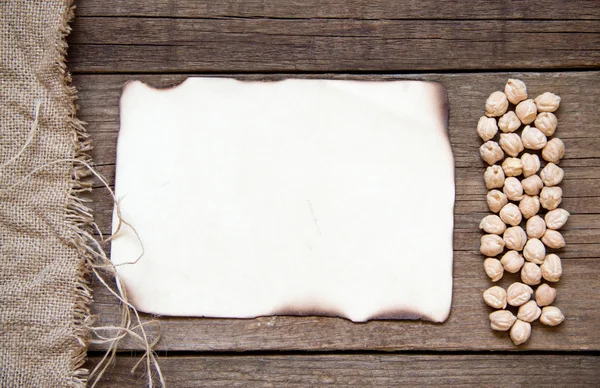 Card, chickpea, burlap and dark wood background