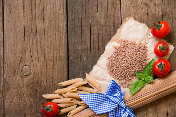 Pasta, tomatoes and basil on wooden background — Stock Photo, Image