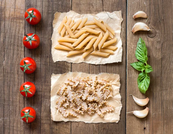 Macarrão, pomodori, aglio e basilico sopra il tavolo di legno — Fotografia de Stock