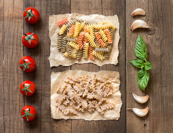 Macarrão, pomodori, aglio e basilico sopra il tavolo di legno — Fotografia de Stock