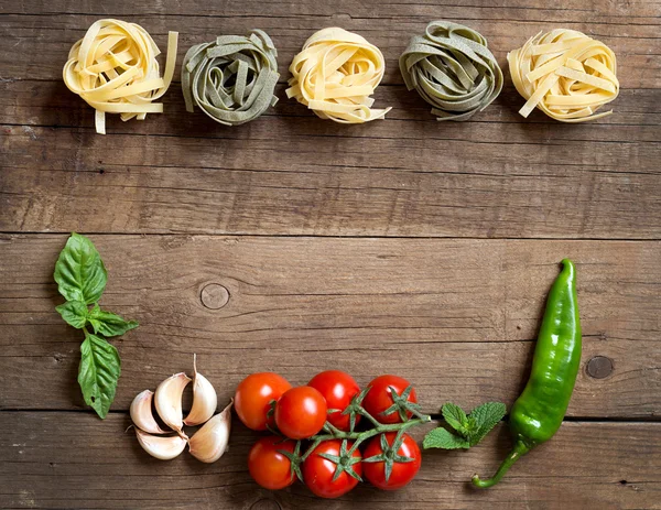 Pastas, verduras y hierbas sobre madera — Foto de Stock