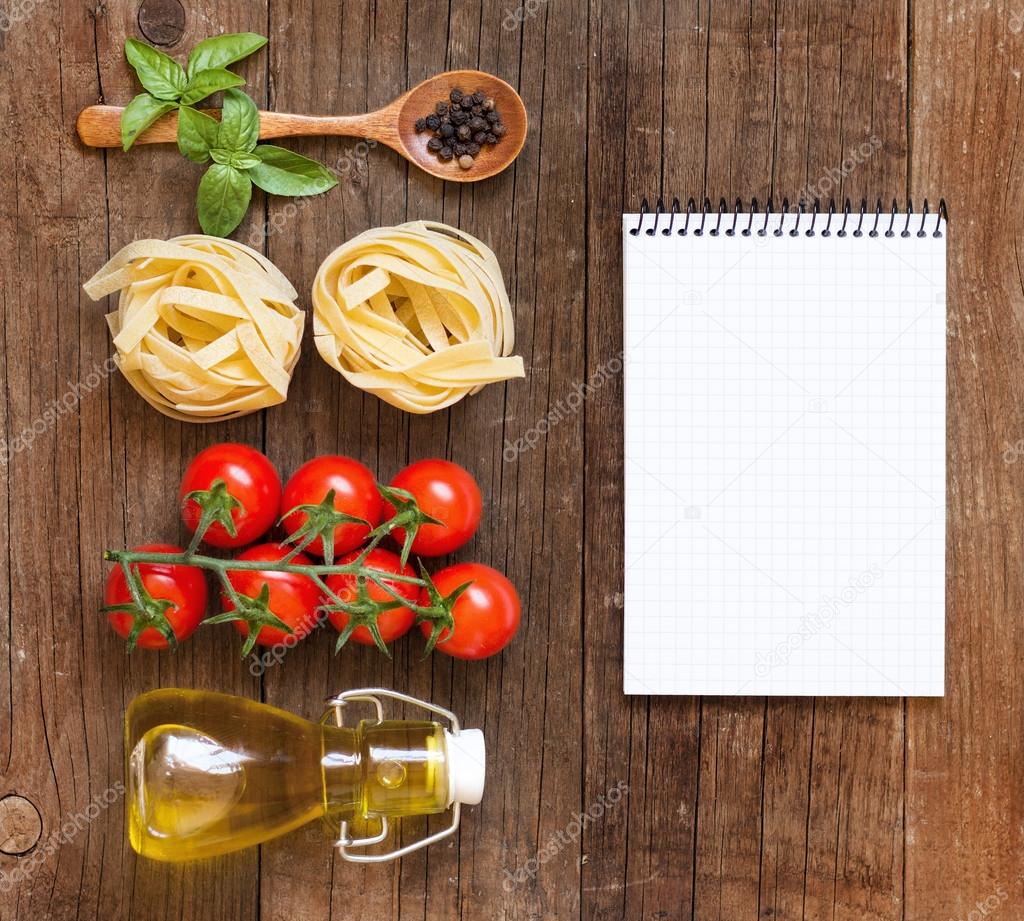 Pasta, vegetables, herbs and notebook on old wooden table
