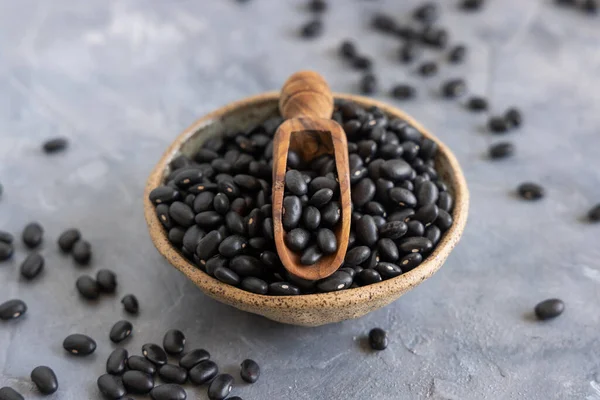 Ceramic Bowl Full Dry Black Beans Wooden Scoop Grey Table — Stock Photo, Image