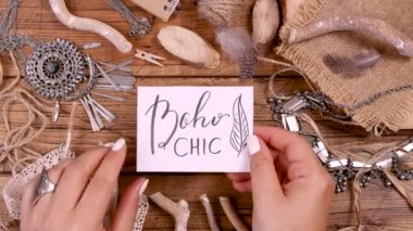 Tahta bir masanın üstünde BOHO CHIC kartı ile el ele 