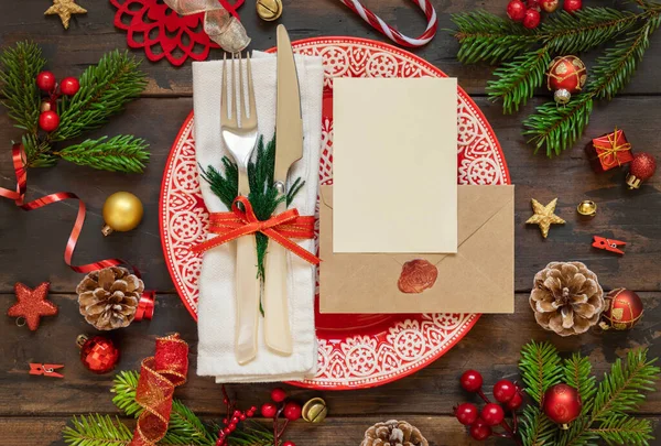 休日の装飾 モミの木の枝 空白のカードと密封された封筒トップビューとお祭りのテーブル設定 茶色の木製のテーブルフラットレイアウト コピースペースのクリスマスや新年のモックアップ 冬休み — ストック写真