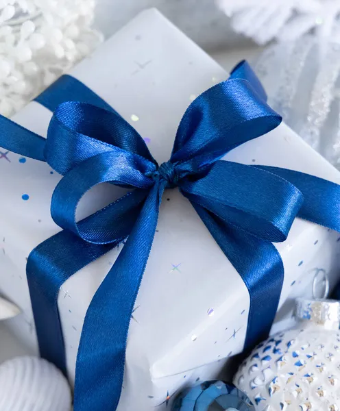 Завернутый Подарок Голубым Луком Белыми Голубыми Серебряными Рождественскими Украшениями Вокруг — стоковое фото