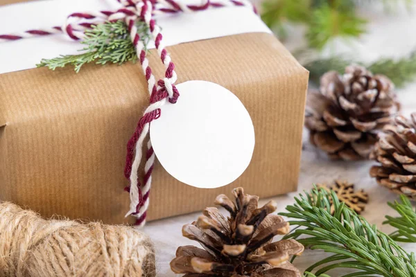 クリスマスには モミの木の枝や装飾が閉じられた白いテーブルの上に丸い紙のギフトタグがプレゼントされました 空白のギフトタグと素朴な冬の組成物 Mockup コピースペース — ストック写真