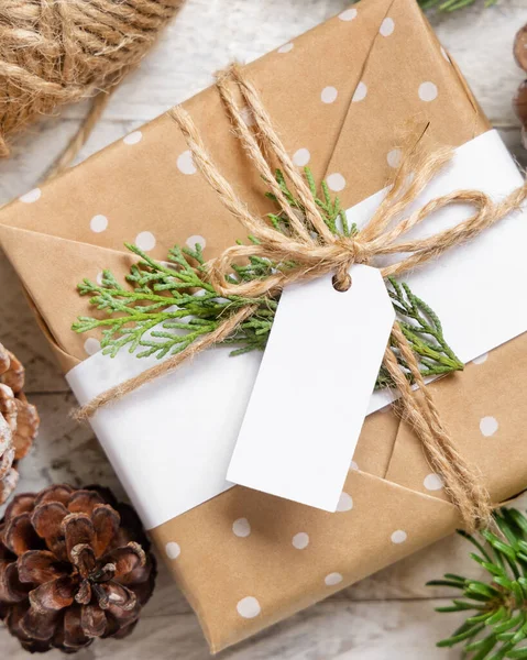 クリスマスは モミの木の枝や装飾トップビューと白いテーブルの上に紙のギフトタグでプレゼントを包んだ 空白のギフトタグと素朴な冬の組成物 Mockup コピースペース — ストック写真