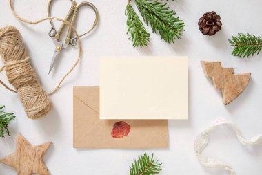 Kış Noel kompozisyonu ve mühürlü zarf düzlüğü. Noel ve Yeni Yıl tebrik kartı şablonu, köknar ağacı dalları ve beyaz ahşap arka plan manzaralı çam kozalakları. Tatil modeli..