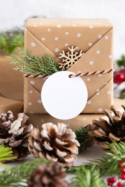 クリスマスには モミの木の枝や装飾が閉じられた白いテーブルの上に丸い紙のギフトタグがプレゼントされました 空白のギフトタグと素朴な冬の組成物 Mockup コピースペース — ストック写真