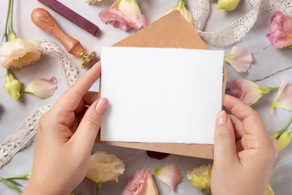 Mão Com Cartão Envelope Sobre Mármore Com Flores Rosa Secas — Fotografia de Stock