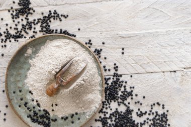 Bir kepçe siyah mercimek unu ve beyaz ahşap masa üstü manzaralı fasulye ile fotokopi alanı. Alternatif un, sağlıklı beslenme, vejetaryen konsepti. Geleneksel Asya ve Kuzey Afrika mutfağı