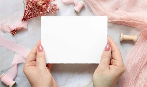 Mãos Com Cartão Branco Sobre Mármore Perto Flores Rosa Secas — Fotografia de Stock