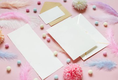 Pastel çiçeklerin yanındaki boş kartlar ve zarf. Yüzüğün yanındaki ponpon ve tüyler. Pembe bir hediye kutusunda. Düğün kırtasiyesiyle romantik bir sahne, düz yazı için mekan. Sevgililer Günü, Bahar ya da kız işi konsept