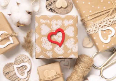 Sevgililer Günü hediyeleri kraft kağıdına sarılıp eski danteller, kalpler ve otlarla süslenmiş. Bahar kırsal, kır evi şıklığı veya bohem konsepti