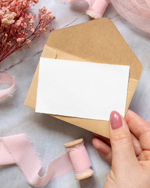 Mão Com Cartão Envelope Sobre Mármore Com Flores Rosa Secas — Fotografia de Stock