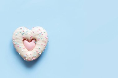 İki kalp şeklinde zencefilli kurabiye serpiştirilmiş ve pembe arkaplanda krema. Sevgililer Günü pastanesinin en güzel manzarası, romantik tatiller için ev yapımı fırın