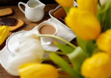 Elegant Coffee tray near white and yellow tulips bouquet on wooden table close up. Romantic breakfast