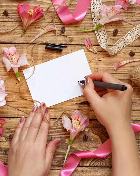 Hands Writing Card Wooden Table Pink Flowers Top View — Fotografia de Stock