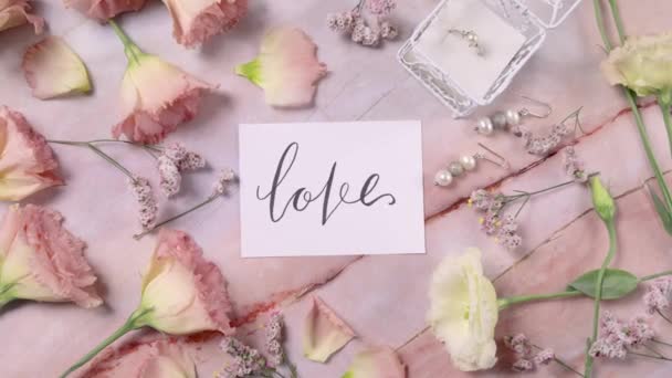 Tarjeta Love Una Mesa Mármol Cerca Flores Rosadas Vista Superior — Vídeos de Stock