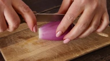 Tahtada taze soğan doğrayan kadın elleri. Yakın çekim, mutfakta yemek pişirme kavramı.