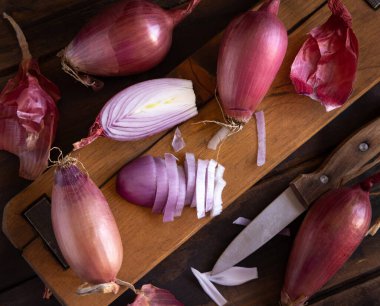 Sliced Red tropea onions with a knife on a wooden board  top view. Traditional local south italian vegetable. Cooking process in home kitchen clipart