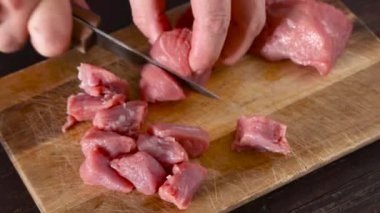 Kadın elleri bir parça çiğ eti metal bir bıçakla dilimlere ayırıyor. Mutfakta yemek pişirme kavramı.