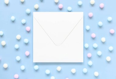 Açık mavi üst manzaralı pastel ponponlar arasında boş bir zarf. Boş yatay kartın olduğu romantik bir sahne, düz yazı için yer var. Bahar ya da çocuksu kavram