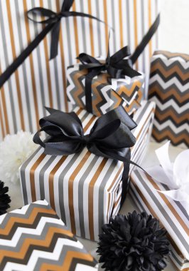 Çizgili ve simgesel geometrik kağıda sarılı hediye kutuları siyah ve beyaz dekoru yakınında siyah kurdeleli. Noel, Yeni Yıl, Doğum günü, Yıldönümü konsepti