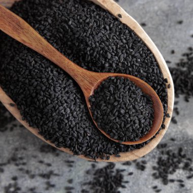 Hint baharatlı kimyon (nigella sativa veya kalonji) tohumları kasede gri masa manzaralı kaşık ile. Geleneksel tıp, sağlıklı ve vejetaryen gıda konsepti.