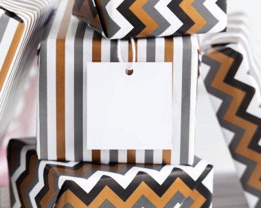 Boş kare hediye etiketi ile yakın çekim. Çizgili ve sembollü geometrik kağıda sarılı hediye kutuları. Noel, Yeni Yıl, Doğum günü, Yıldönümü Modeli