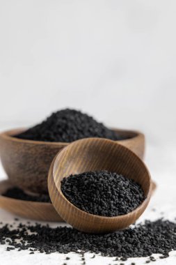 Hint baharatlı kimyon (nigella sativa veya kalonji) tohumları tahta kaselerde fotokopi alanı ile kaplıdır. Geleneksel tıp, sağlıklı ve vejetaryen gıda konsepti.